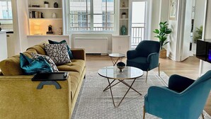 Ein modernes Wohnzimmer mit einer Couch, Sesseln, einem Couchtisch und einem Bücherregal.