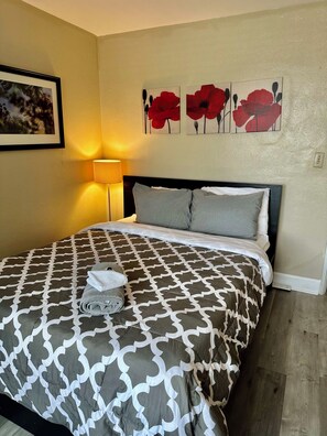 A hotel room with a bed, a lamp, and three wall-mounted flower paintings.