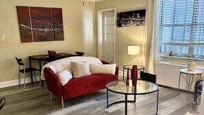 Una sala de estar moderna con un sofá rojo, una mesa de centro de vidrio y un ventilador de techo.