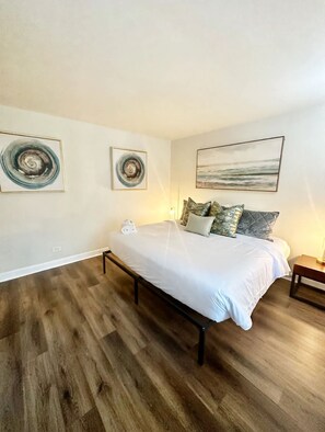 A bedroom with a bed, pillows, a nightstand, and artwork on the walls. - FIFA 2026 Walk to Stadium | 1BR Unit 12K ATL (Atlanta)
