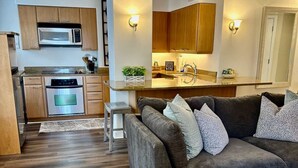 A modern kitchen with wooden cabinets, a built-in microwave, and a central island with a sink.