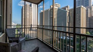 A balcony with wicker furniture and a view of high-rise buildings.