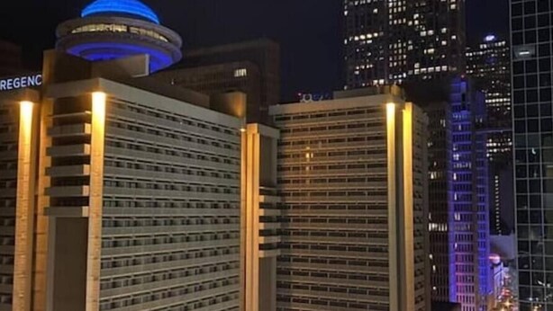 A high-rise building with a prominent circular structure on top, likely a hotel or office building, with multiple floors and a modern design.