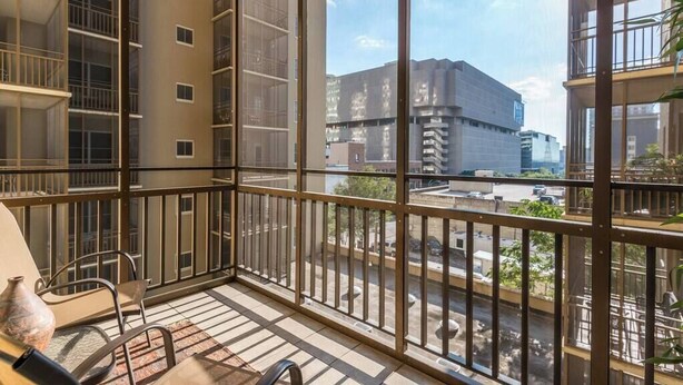 A balcony with a view of a cityscape, including a large building with multiple floors and a parking lot below. - FIFA 2026 Walk to Stadium | 2BR Unit 4G ATL (Atlanta)