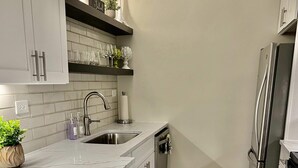 A modern kitchen with white cabinets, a stainless steel refrigerator, and a marble countertop. - FIFA 2026 Walk to Stadium | 2BR Unit 21G ATL (Atlanta)
