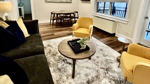 A living room with a dark green sofa, a yellow armchair, and a round coffee table with a tray and plant. - FIFA 2026 Walk to Stadium | 2BR Unit 21G ATL (Atlanta)