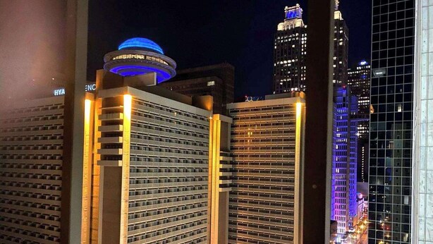 Vista nocturna de un paisaje urbano con edificios altos, incluyendo un hotel con una cúpula distintiva y ventanas iluminadas.