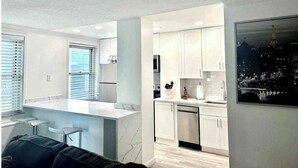 Una cocina moderna con armarios blancos, encimera de mármol y lavavajillas.