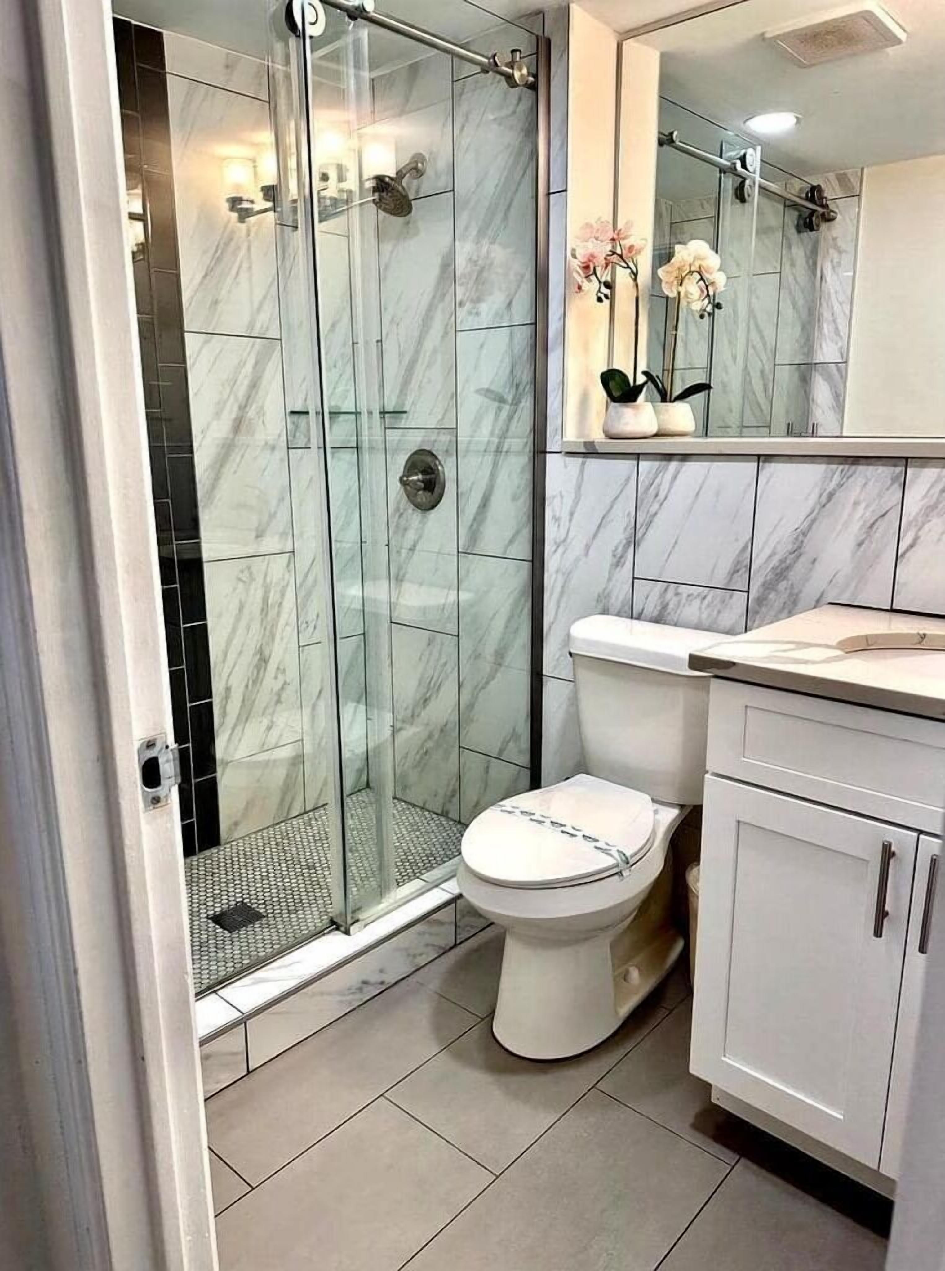 A modern bathroom with a glass-enclosed shower, a toilet, and a vanity with cabinets.