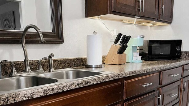 Una cocina con un lavamanos doble, un microondas y armarios de madera.