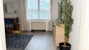 Un espacio habitable moderno con zona de comedor, un ventanal con persianas, una planta en maceta y un radiador.