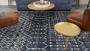 Un salón con un sofá, dos mesitas auxiliares, una mesa de centro y dos sillones.