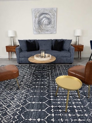 Un salón con un sofá, dos mesitas auxiliares, una mesa de centro y dos sillones.