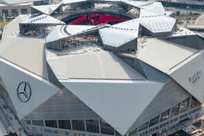 A modern architectural structure with a distinctive angular design, featuring a prominent Mercedes-Benz logo on one side. - Comfortable Downtown 1BR | Walk to the Stadium (Atlanta)