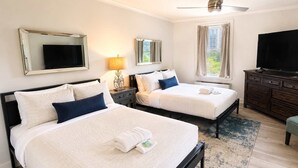 A hotel room with two beds, a TV, a ceiling fan, a window with curtains, and a dresser. - FIFA 2026 Walk to Stadium | 1BR Unit 4E ATL (Atlanta)