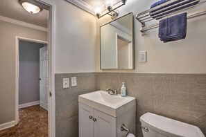A bathroom with a white sink, a mirror, a towel rack, and a toilet. - 8E Cozy Condo in Downtown Atlanta Hotel District! (Atlanta)