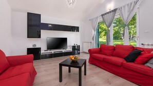 A modern living room with a red sofa, a black coffee table with fruit, a flat-screen TV, and a chandelier. - Villa Kristina (Istria - Pazin) (Pazin)