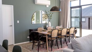 A dining area with a round table, chairs, and a mirror on the wall. - Sunset On Syrah, Martinborough (Martinborough)