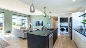 A modern kitchen with a central island, built-in appliances, and pendant lighting. - Sunset On Syrah, Martinborough (Martinborough)