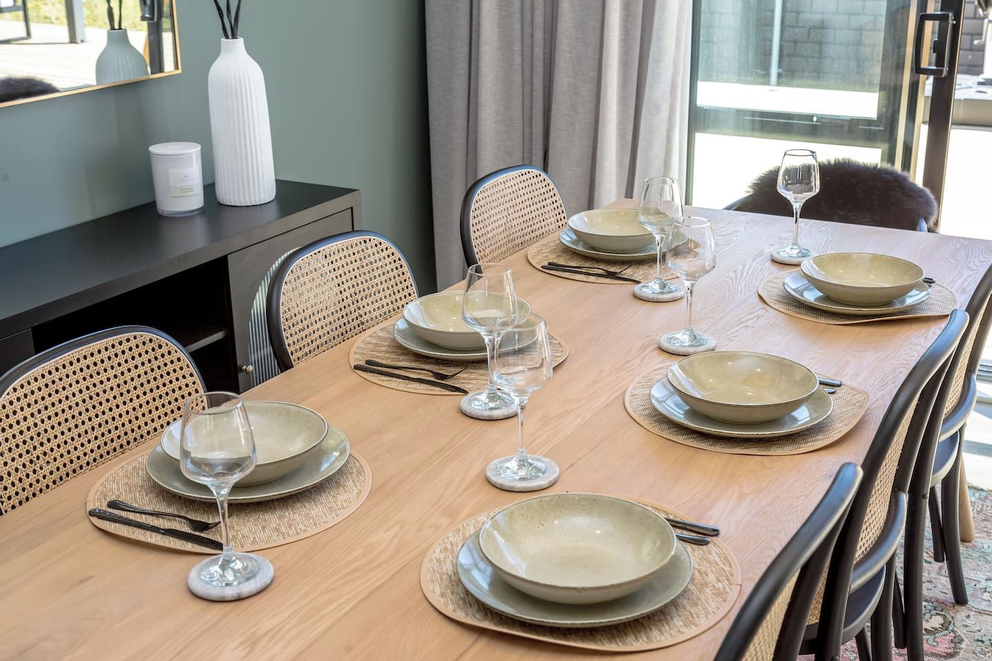 A dining table set for six with plates, glasses, and cutlery.
