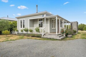 A single-story house with a porch, a chimney, and a small garden area. - Applecross Cottage, Martinborough (Martinborough)