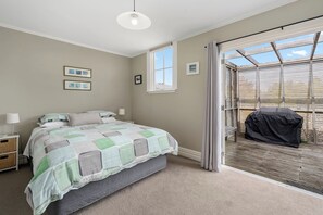 Une chambre à coucher comprenant un lit, des tables de chevet, une fenêtre et donnant sur un espace extérieur.