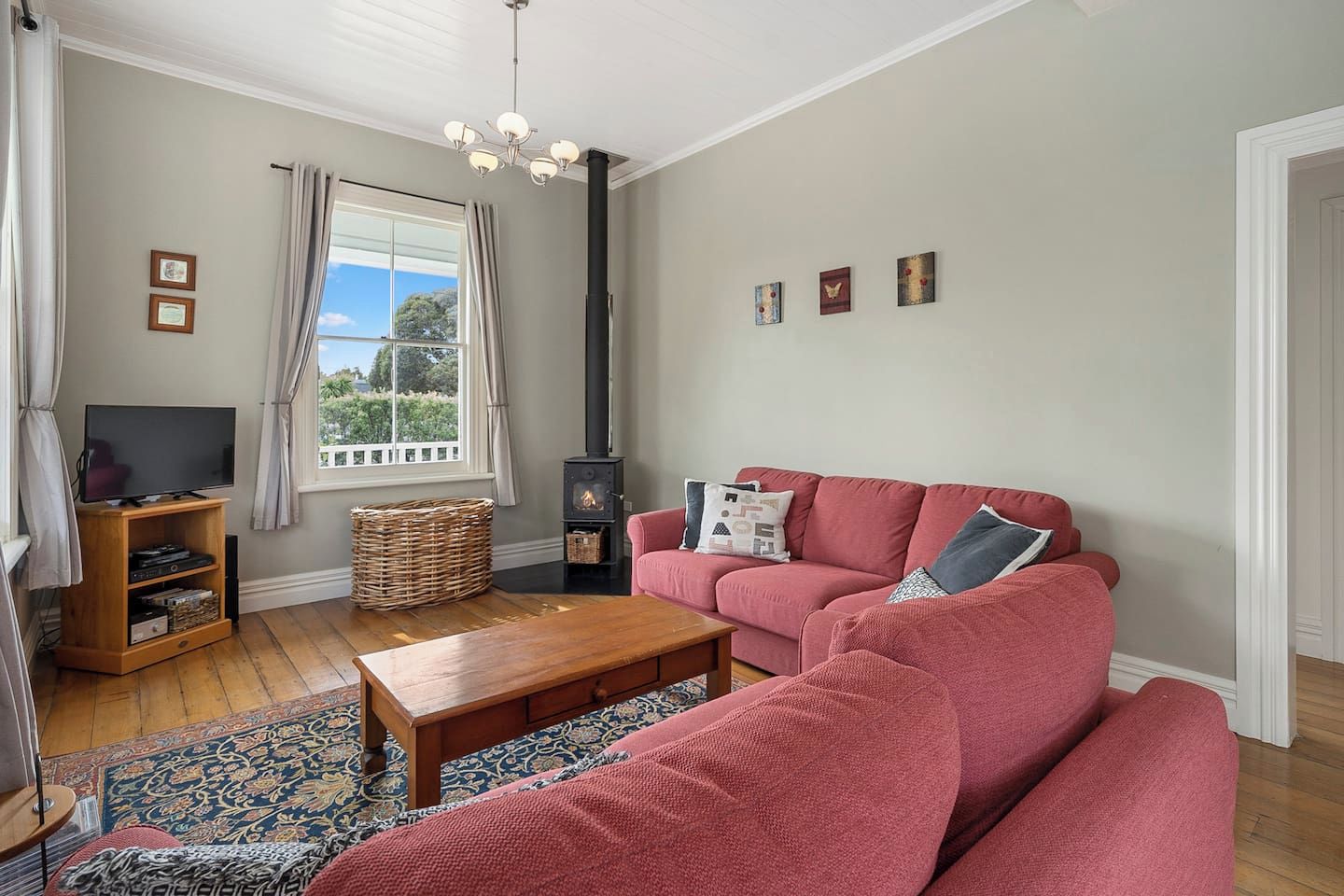 A living room with a sofa, a television, a fireplace, and a window with curtains.