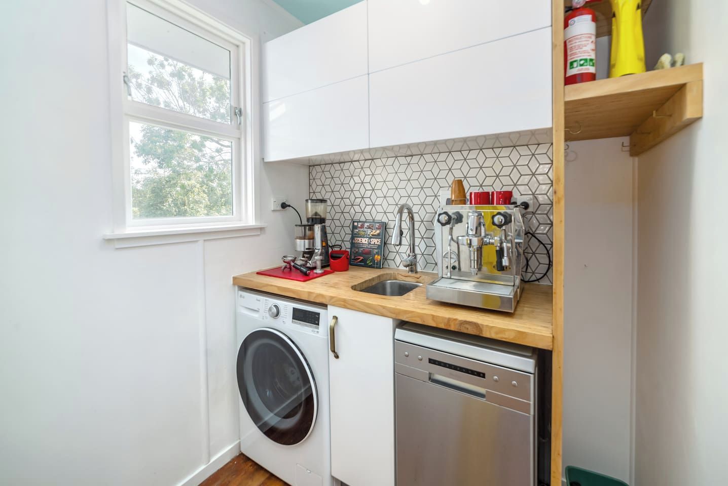 A compact kitchen with a washing machine, dishwasher, and a coffee machine.