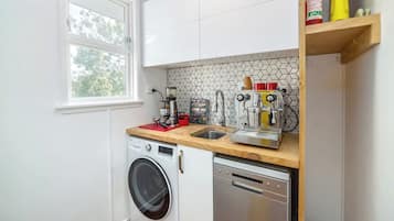 A compact kitchen with a washing machine, dishwasher, and a coffee machine.