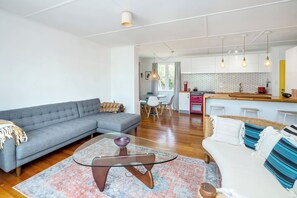 A modern living room with a grey sofa, a glass coffee table, and a patterned rug. - Little Blue Bach, Martinborough (Martinborough)