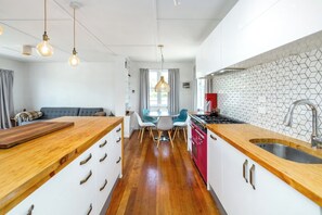 A modern kitchen with a wooden island, a dining area with chairs, and a red stove.