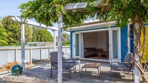 Un patio exterior con pérgola, zona de estar y puerta corrediza de vidrio que da a un espacio interior.