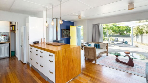 Una cocina moderna con una isla de madera, armarios blancos e iluminación colgante.
