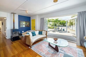 A modern living room with a sofa, glass coffee table, and a wood-burning stove.