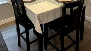 A dining table set for four with black chairs, a white tablecloth, and a vase of white flowers in the center. - Renovated and Comfortable-South Meridian

 (Meridian)