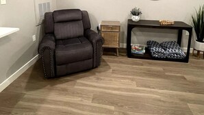 A modern living room with a leather recliner, a small wooden side table, a round mirror, and a welcome sign. - Renovated and Comfortable-South Meridian

 (Meridian)