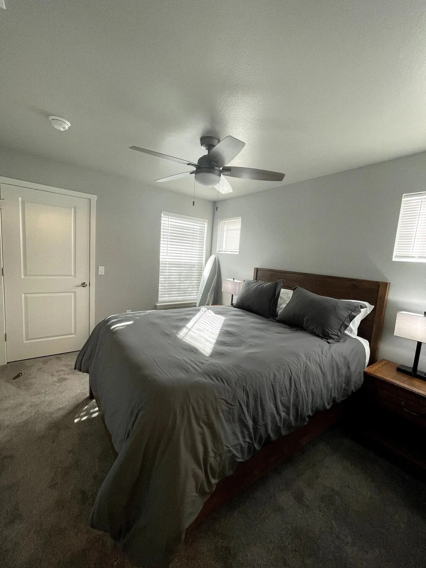A bedroom with a bed, ceiling fan, and two bedside lamps.