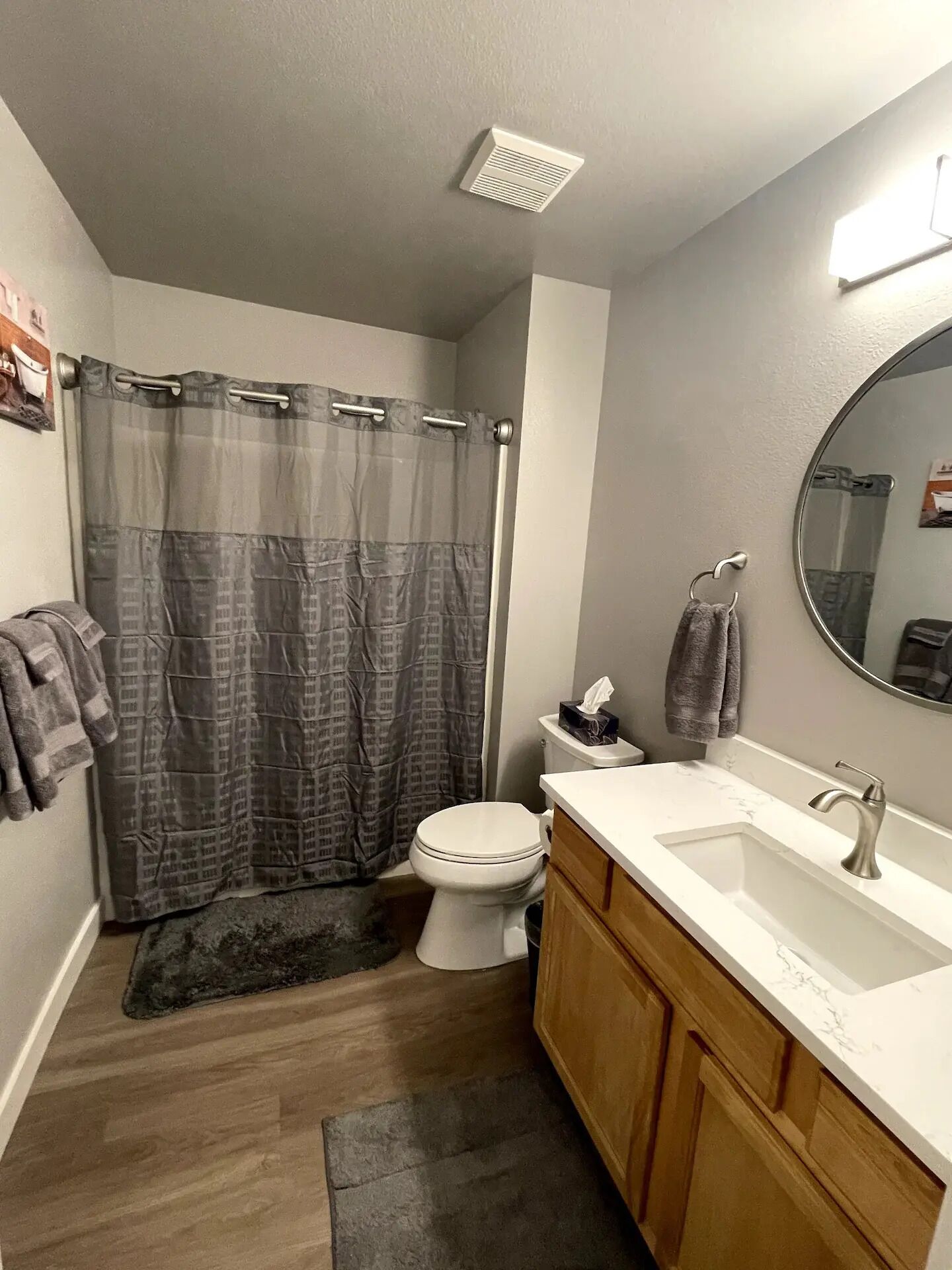A bathroom with a shower curtain, toilet, sink, and mirror.