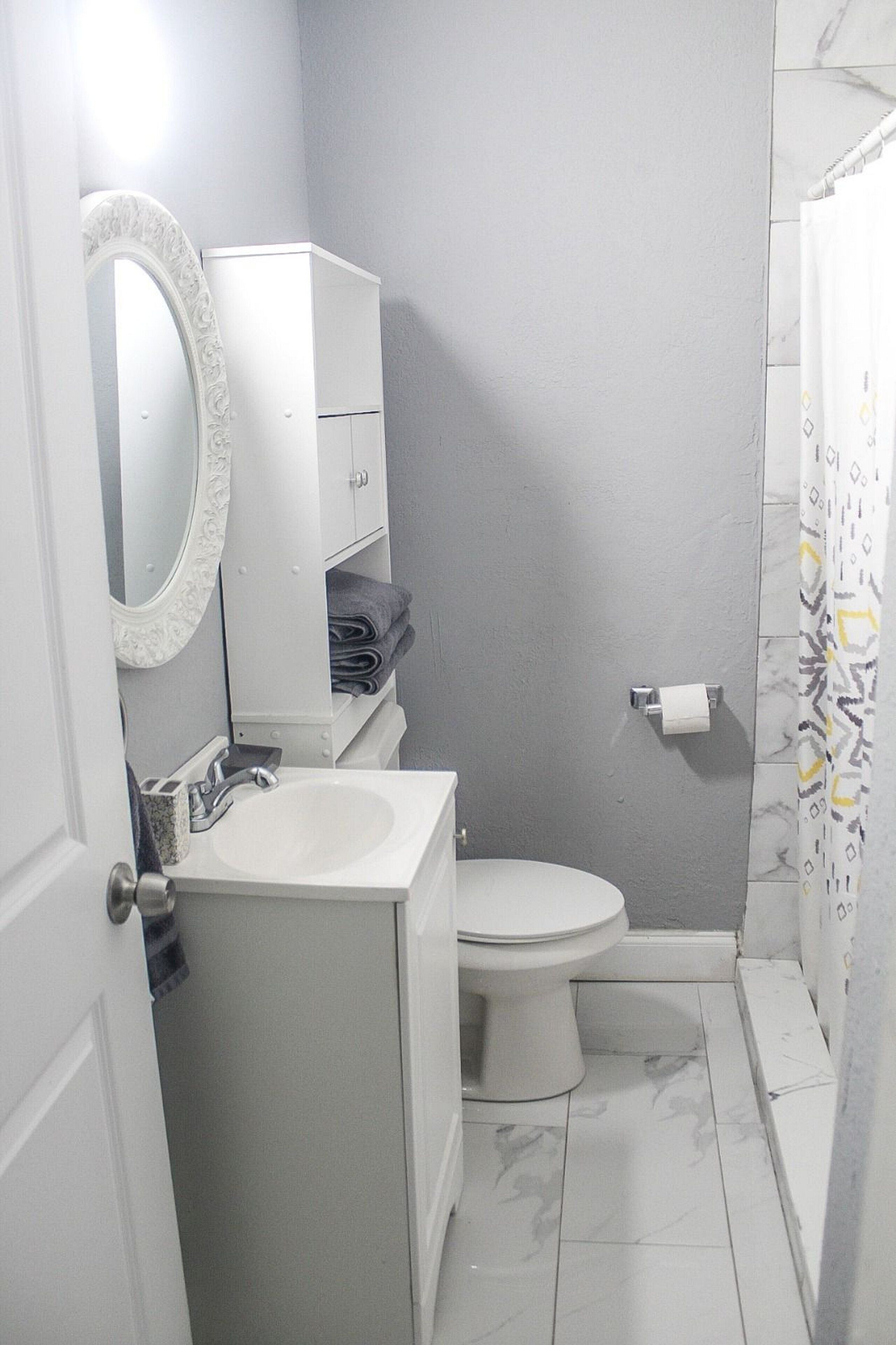 Une salle de bain avec un lavabo blanc, des toilettes et un meuble avec un miroir.