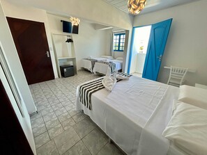 A hotel room with a bed, a desk, a chair, a wardrobe, and a TV. - KYROS POUSADA (Maceió)