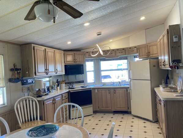 A kitchen with wooden cabinets, a stove, a refrigerator, and a dining area with chairs and a table.