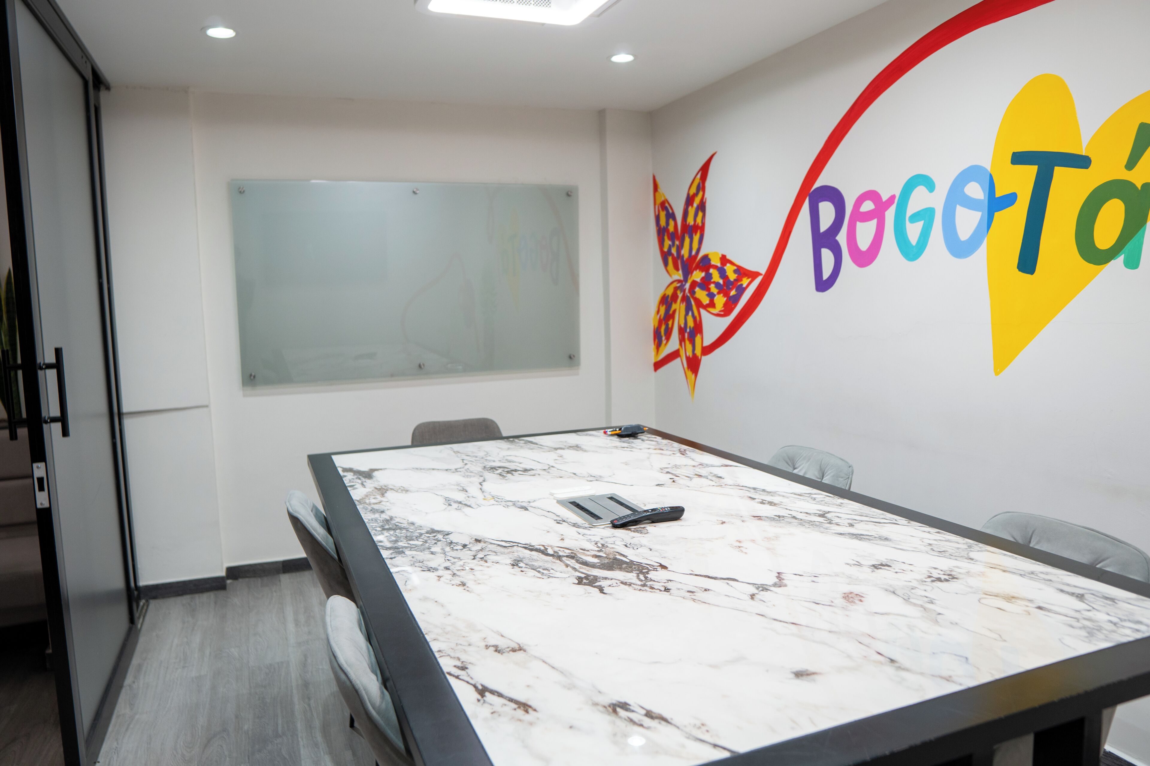 Une salle de conférence dotée d’une table en marbre, d’un tableau blanc et d’une décoration murale aux couleurs vives.