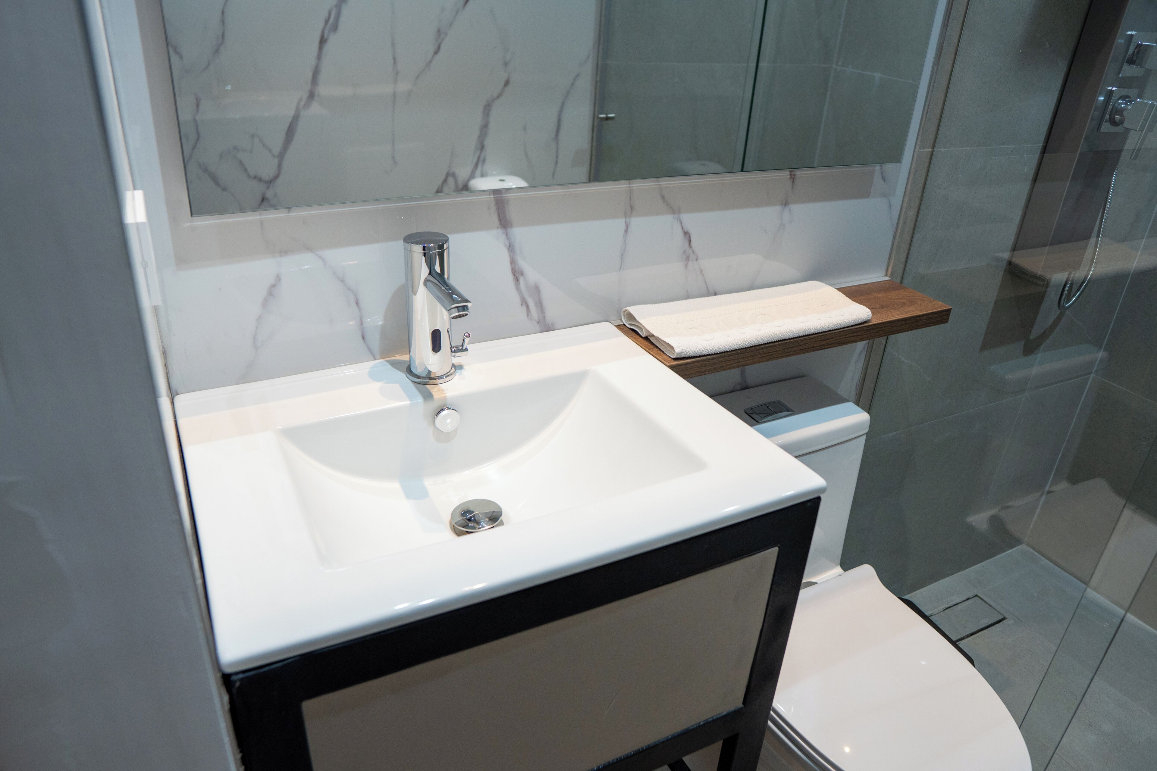A bathroom with a white sink, a mirror, and a glass shower enclosure.