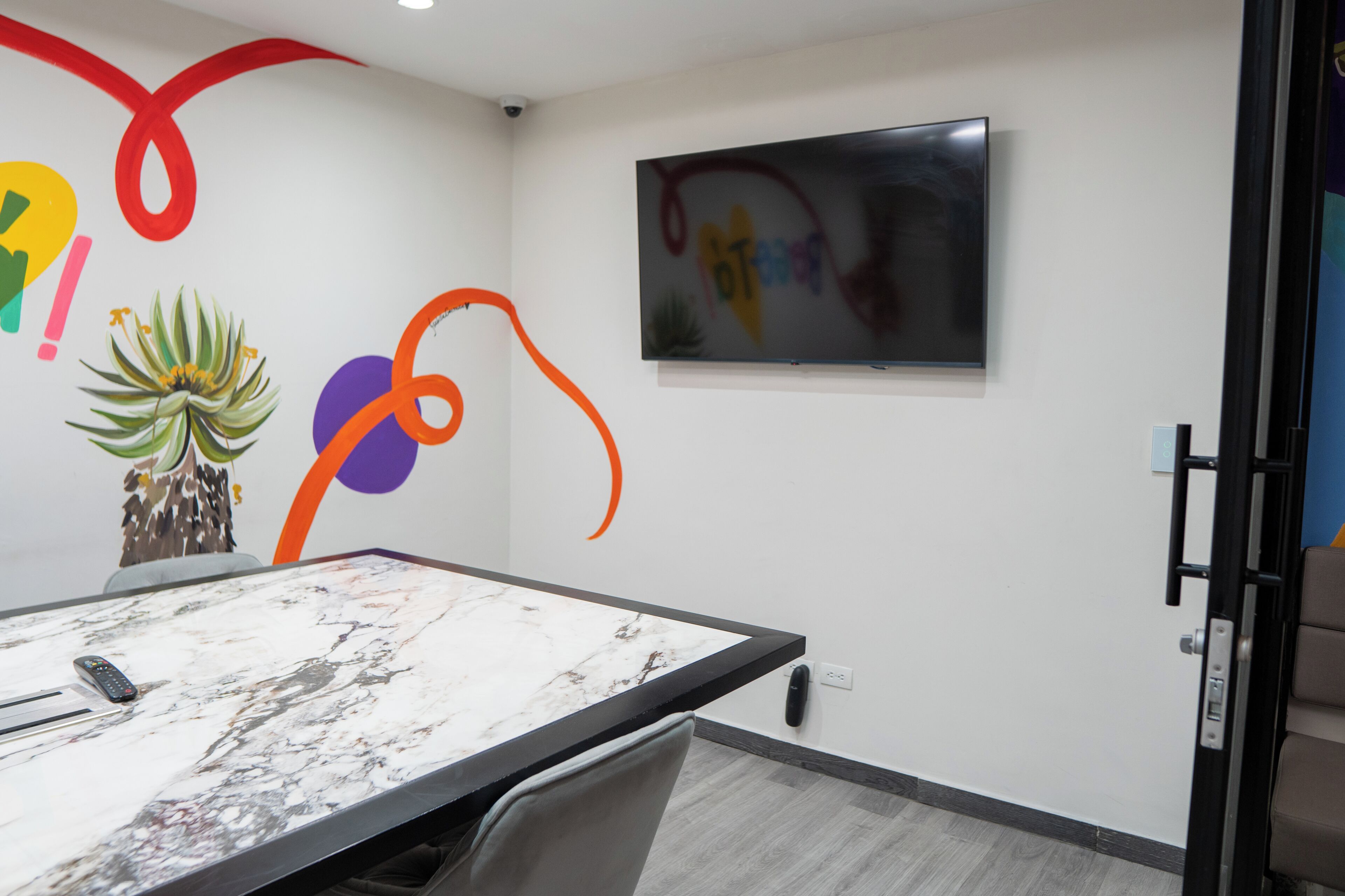 Une salle de conférence dotée d’une table en marbre, d’un téléviseur fixé au mur et d’œuvres d’art abstraites.