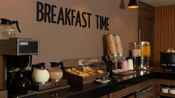 Un bar pour le petit-déjeuner équipé d’une machine à café, d’un distributeur de céréales et d’un distributeur de boissons.