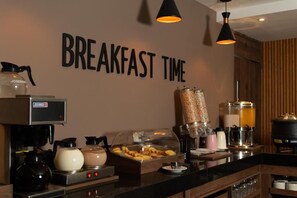Un bar pour le petit-déjeuner équipé d’une machine à café, d’un distributeur de céréales et d’un distributeur de boissons.