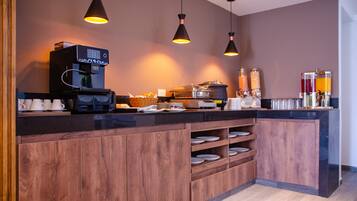 A modern kitchen with a coffee machine, shelves with plates, and hanging pendant lights.