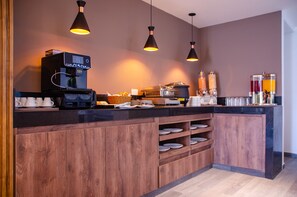 Una cocina moderna con una cafetera, estantes con platos y lámparas colgantes.