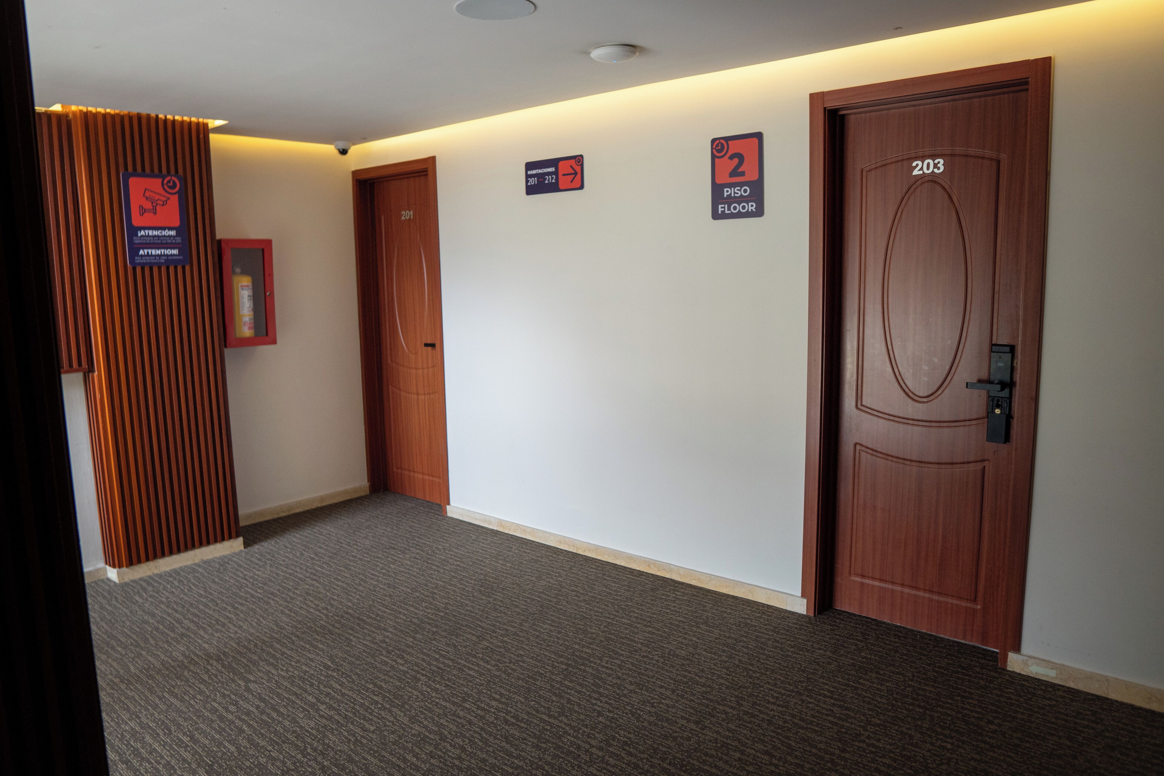 Un pasillo con dos puertas, una con el número '203' y otra con un cartel de '2' que indica el segundo piso.