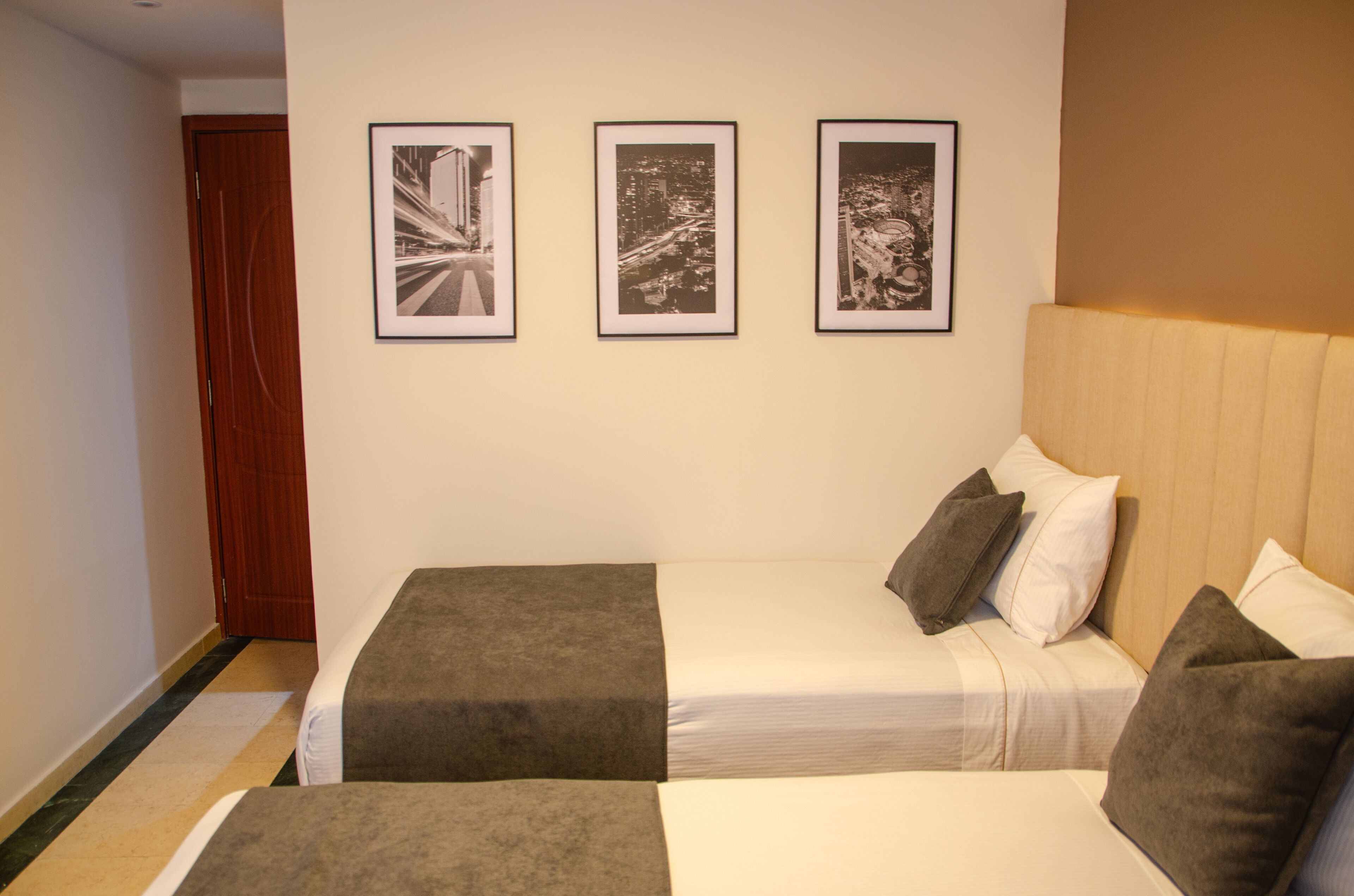 A hotel room with a bed, a sofa, and three framed pictures on the wall.